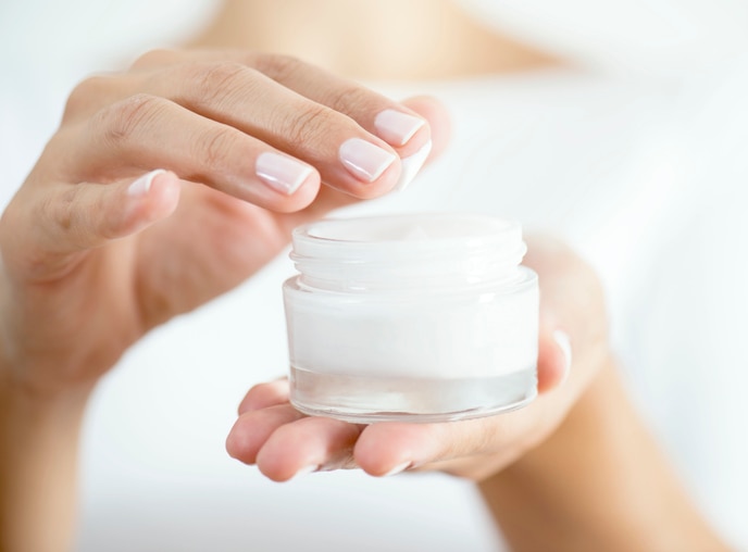 Female hand holding moisturizer in hand, horizontal