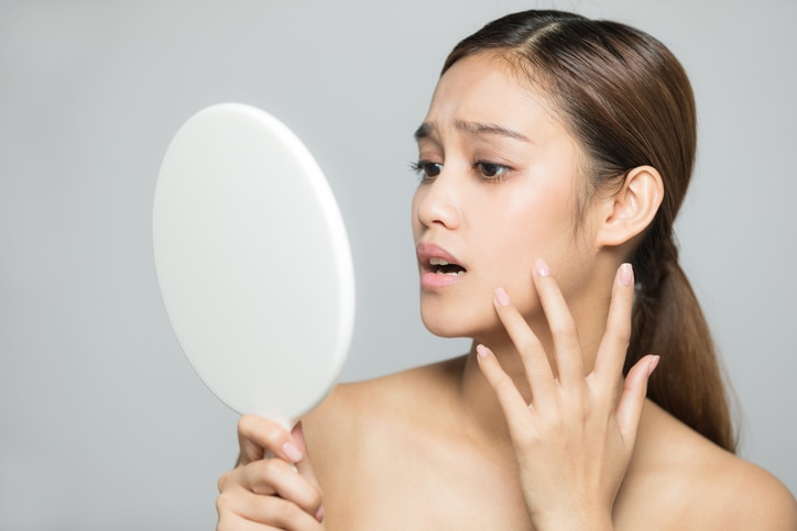 Young woman checking her skin. Skin care concept.