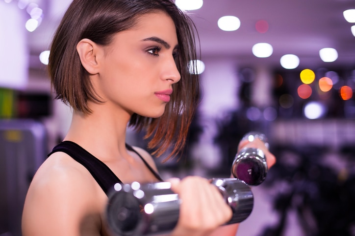 Beautiful girl preparing for workout in the gym with blurred lights in the background, shallow dof