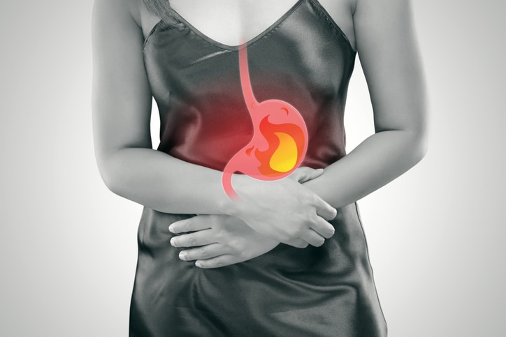 Acid reflux or Heartburn, The photo of stomach is on the woman's body against gray Background, Bad health, Female anatomy concept