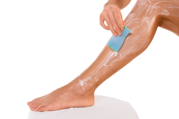 Body hygiene: Woman depilates - scrubs hair removal cream off her leg