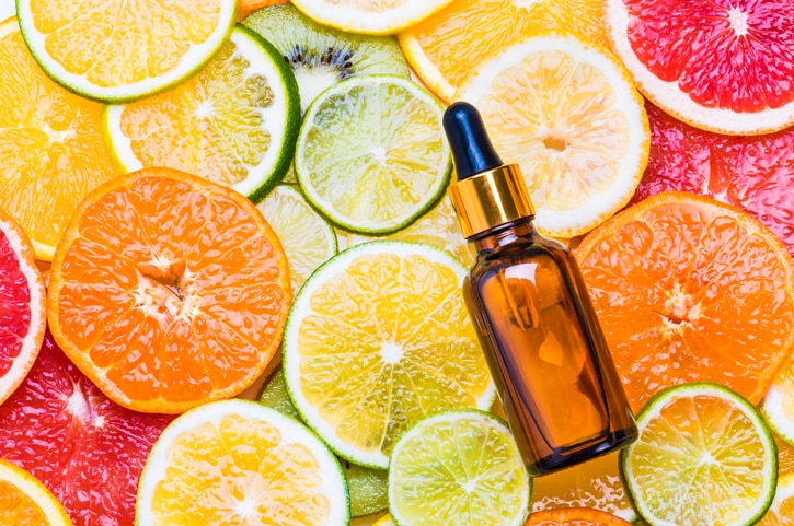 Citrus fruit essential oil bottle with dropper or vitamin c organic cosmetic on citrus background top view.