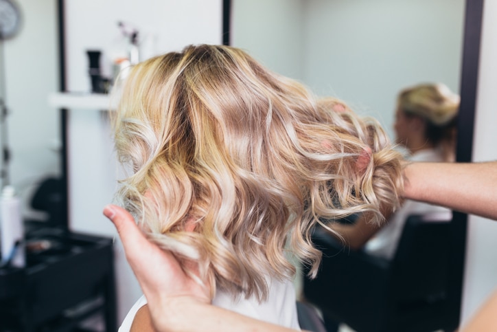 Beautiful hairstyle of young woman after dying hair and making highlights in hair salon.