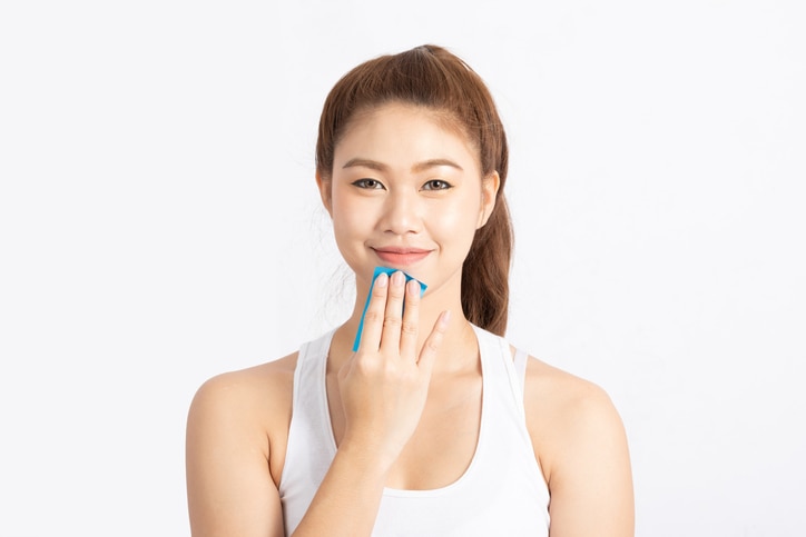 Beautiful Attractive Asian woman using Facial oil clean film to removal oily on face for face fresh skin feeling so fresh and clean,Beauty Concept,Isolated on grey background