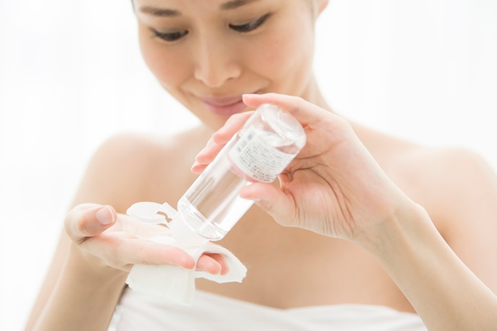 A woman doing skin care with cosmetic lotion.