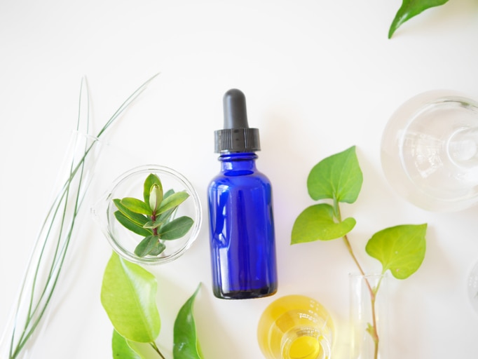 natural skincare cosmetic bottle container and organic green leaf , flowers ingredients with the laboratory glassware on white background. Home made remedy and beauty product concept.