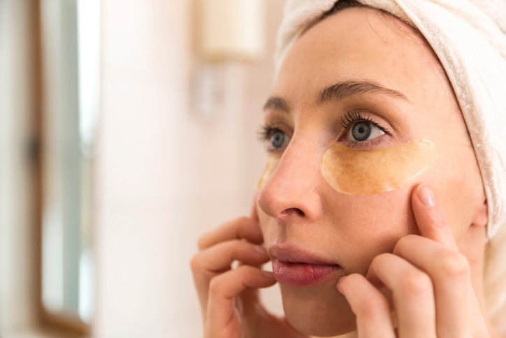 Woman doing facial treatment with eyelid patches at home. Beauty concept