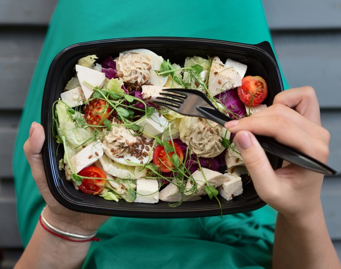 Food delivery service. Woman eating healthy food at lunch time, pov shot