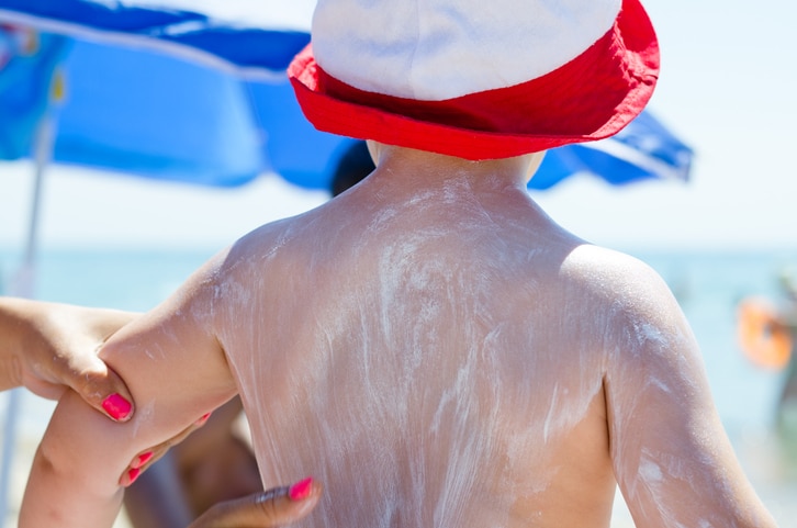 Mother applying sun screen lotion on her child.