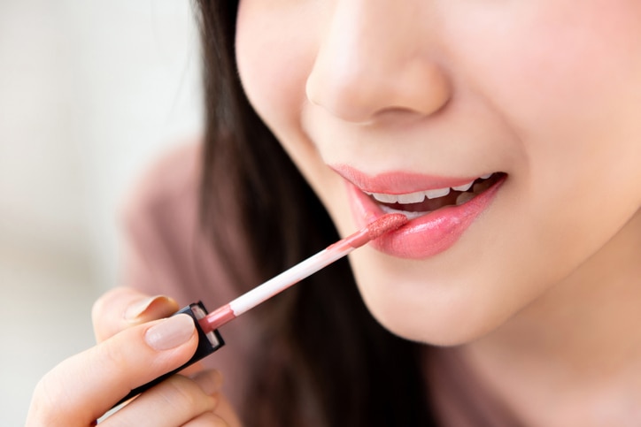 Young beautiful woman professional beauty vlogger or blogger applying lipstick cream to her mouth, doing cosmetic makeup tutorial