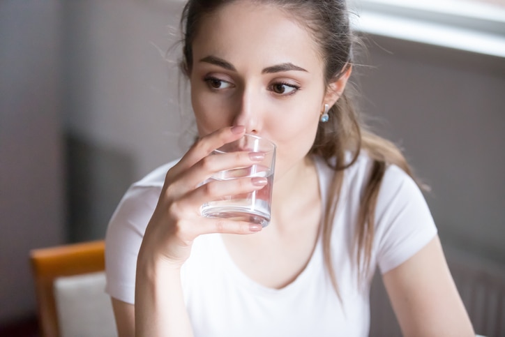 Close up portrait pensive serious millennial woman holding glass drink still water. Beautiful healthy pensive female on diet starting day with fresh natural water healthy lifestyle good habit concept