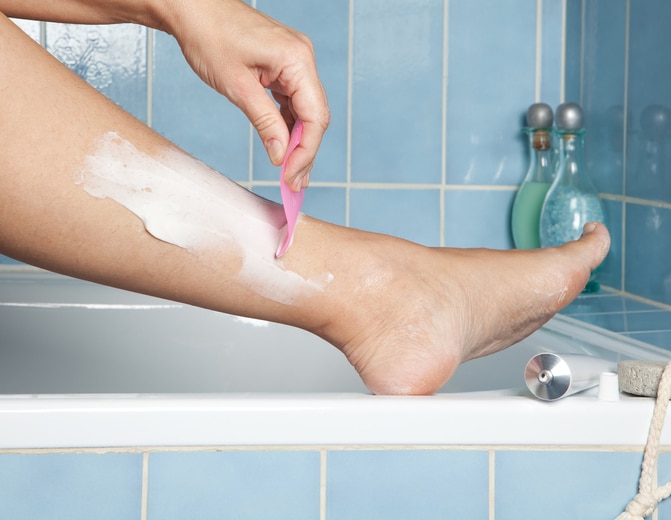 Woman's hands shaving her legs with depilatory cream