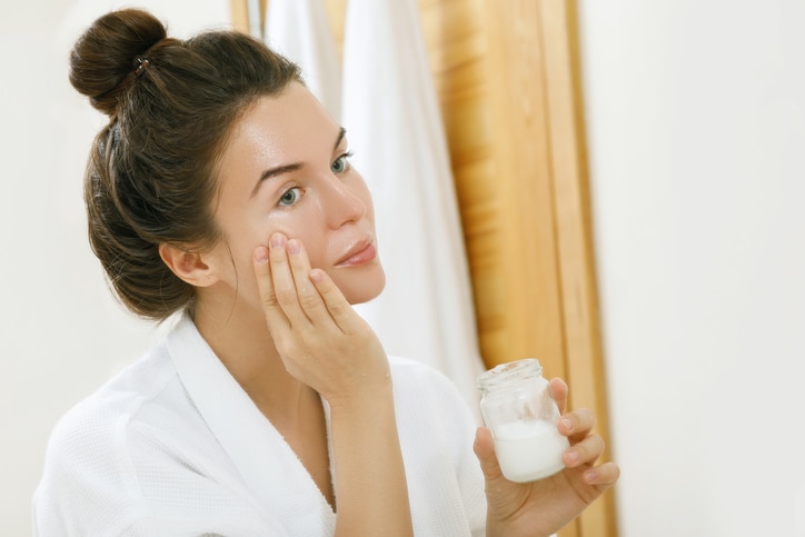 Woman is moisturising her skin with a coconut oil