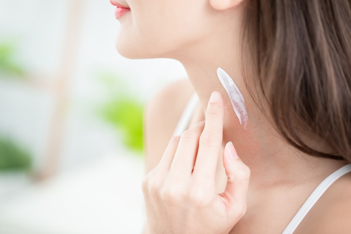 young beauty woman applying cream or sunscreen on her neck