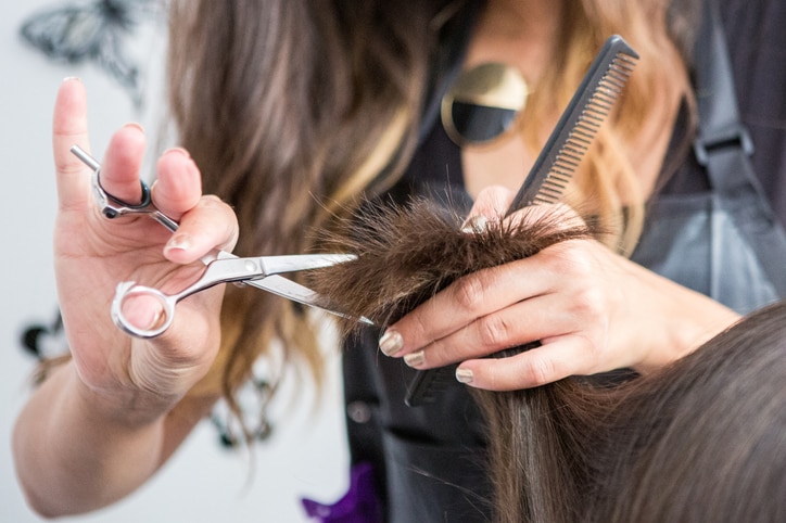 close up of a hairdressers hands cutting wet hair in a hair salon.