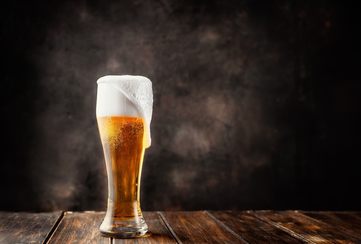 Glass of fresh and cold beer on dark background. Copy space.