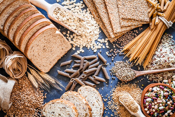 Top view of wholegrain and cereal composition shot on rustic wooden table. This type of food is rich of fiber and is ideal for dieting. The composition includes wholegrain sliced bread, wholegrain pasta, oat flakes, flax seed, brown rice, mixed beans, wholegrain crackers and spelt. Predominant color is brown. DSRL studio photo taken with Canon EOS 5D Mk II and Canon EF 100mm f/2.8L Macro IS USM