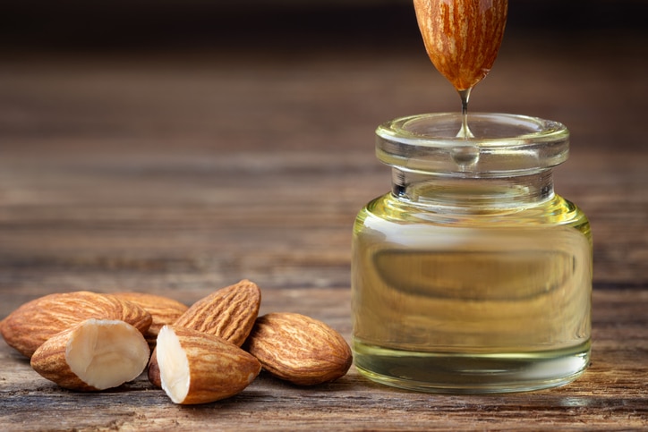 Almond oil in bottle and nuts on wooden table