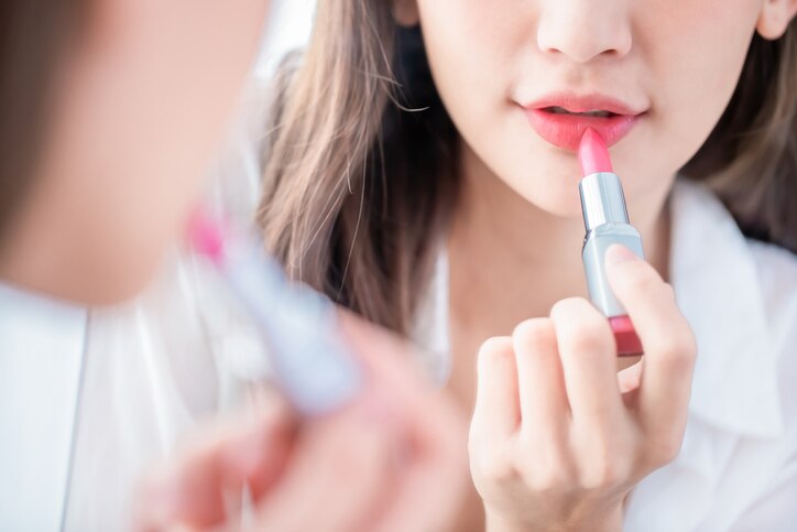 close up of the beauty woman applying lipstick and looking at mirror