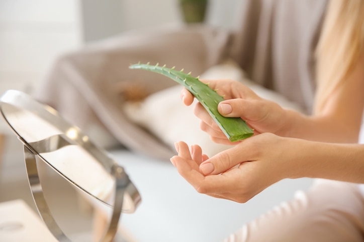 Beautiful young woman using aloe vera at home, closeup