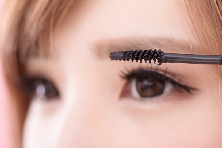 beauty woman take mascara on the pink background