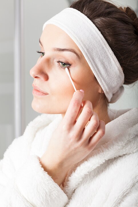 Woman in white bathrobe removing make-up