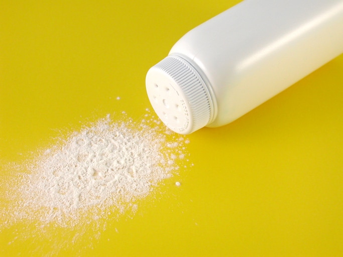 a container of spilled baby powder isolated on yellow background.