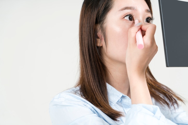 young asian businesswoman applying makeup on her eyes,studio shot.