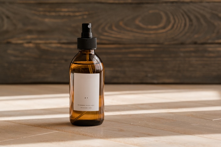 One cosmetic dark amber glass bottle with white lable on wooden table. Closeup, copyspace. Beauty blogging, salon treatment concept, minimalism brand packaging mock up