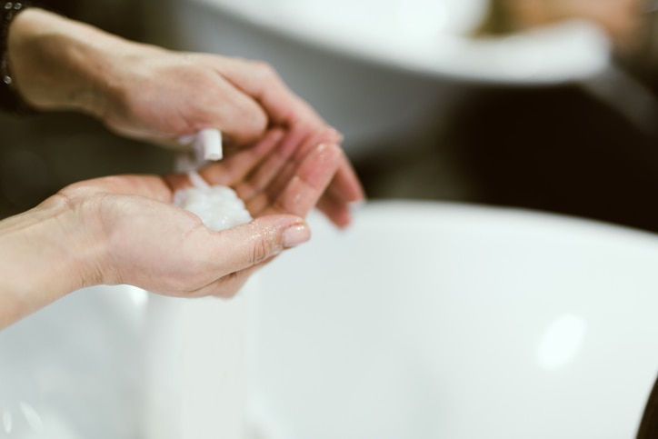 stylist squeezes balsam on his hand