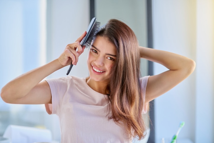 Cropped portrait of a beautiful young woman brushing her hair in the bathroom at home