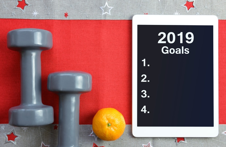 Dumbbells with mandarin and tablet computer. Healthy resolutions for the New Year 2019.