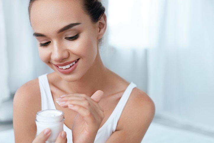 Beauty Skin Care. Beautiful Woman Applying Cream On Healthy Face Skin Portrait. High Resolution.