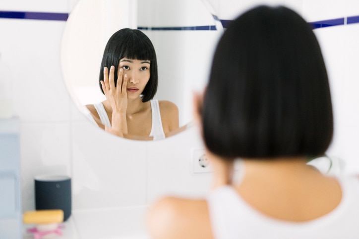 Young beautiful Asian woman looking at mirror in the morning.