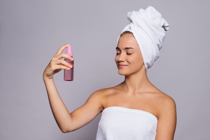 A portrait of a young woman with spray in a studio, beauty and skin care concept.