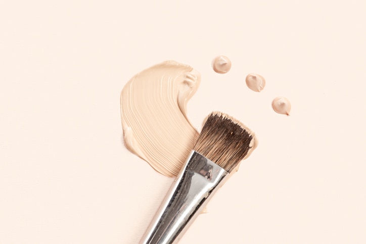 Cosmetic foundation cream and powder with brush on white background