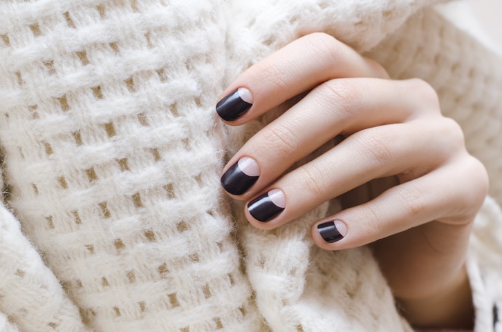 Female hands with dark brown nail design.