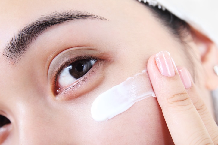 Asian woman applying facial lotion or moisturizer on her face.Close up.