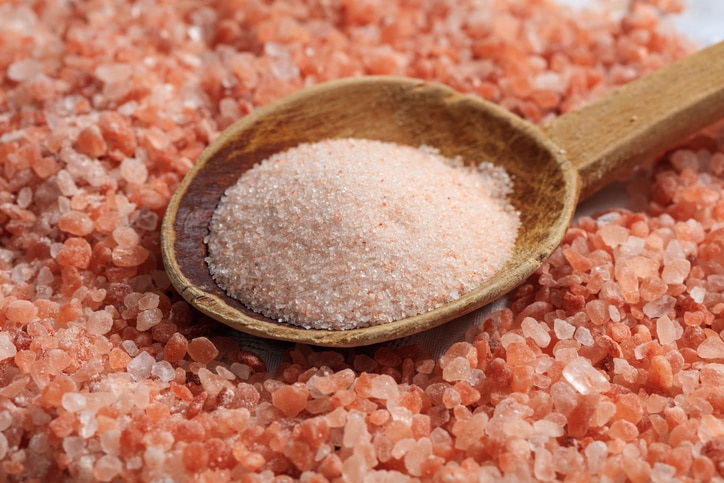 Wooden spoon on pink Himalayan salt background