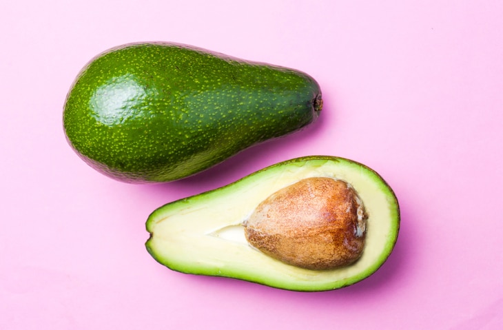 Avocado slices on pink background. Healthy food