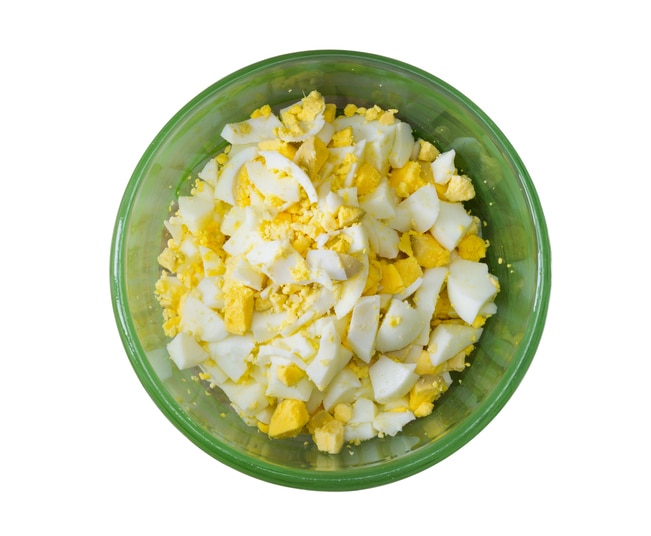 finely chopped boiled eggs in a green bowl isolated on white background. close-up, top view, tinted photo