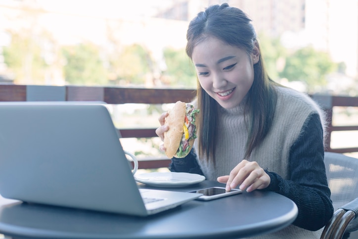 woman having lunch in cafe with laptop on table.