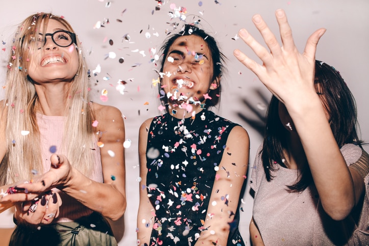 Photo of a group of young women celebrating their youth, femininity and friendship - tossing a confetti in the air while dancing