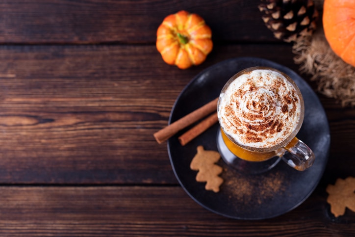 Pumpkin smoothie, spice latte. Boozy cocktail with whipped cream on top on a wooden background. Copy space Top view