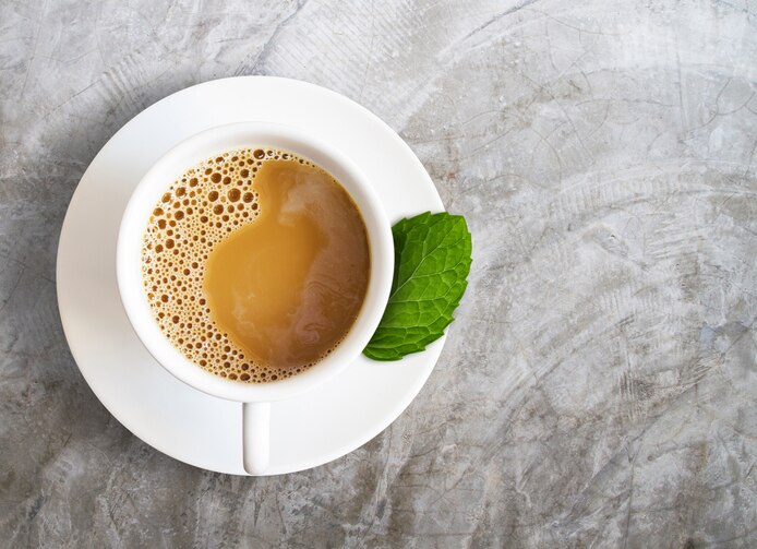 white coffee cup with peppermint leaf isolated on cement background, herbal drink concept