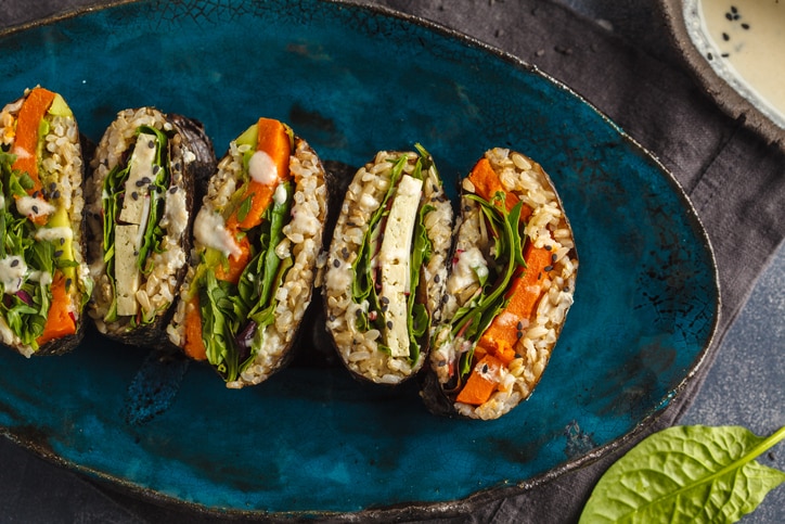 Vegan sushi sandwich onigirazu with tofu and vegetables. Colorful japan sandwich onigirazu with tofu, sweet potato, avocado and tahini. Trend vegan food concept.