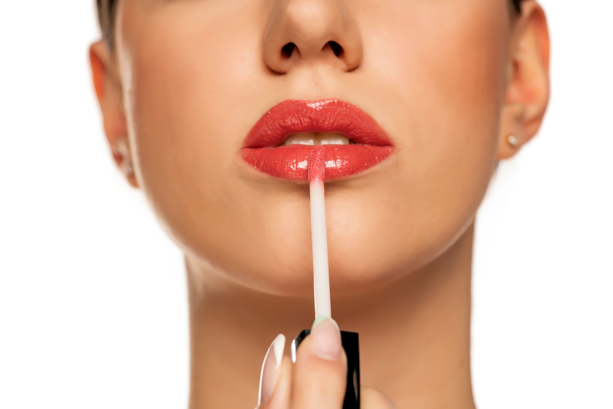 Closeup of woman applying a lip gloss on her lips on a white background, What’s the difference - lipstick, lip powder, lip balm & lip gloss