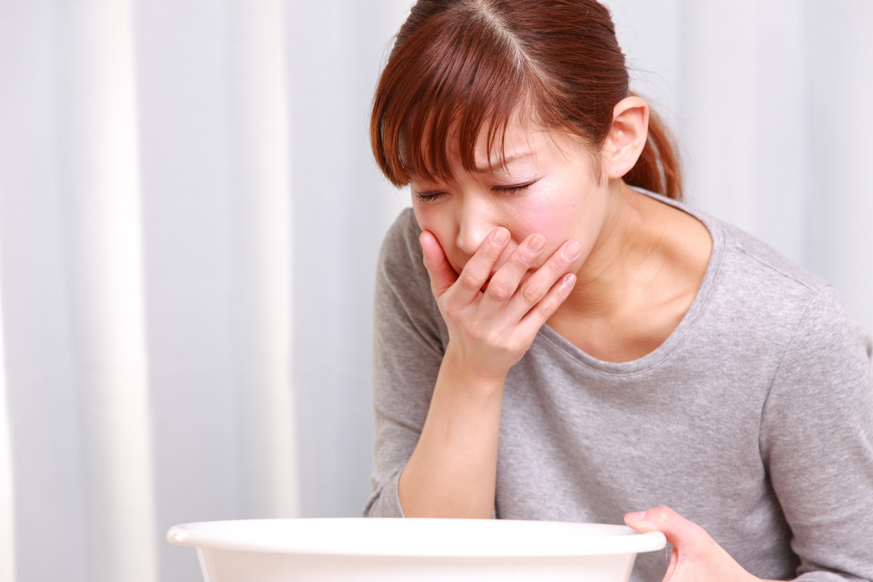 Young woman looking nauseous with hand over mouth